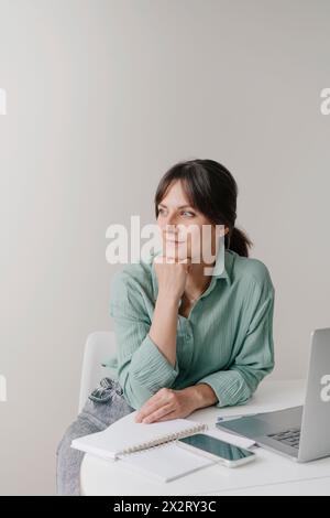 Besinnliche Geschäftsfrau mit Hand am Kinn im Home Office Stockfoto