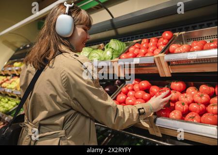 Junge Frau, die Tomaten im Supermarkt aussucht Stockfoto