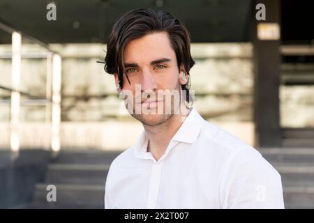 Selbstbewusster junger Geschäftsmann mit schnurlosen in-Ear-Kopfhörern Stockfoto