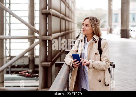 Frau, die ein Smartphone hält und am Bahnhof gelandet ist Stockfoto