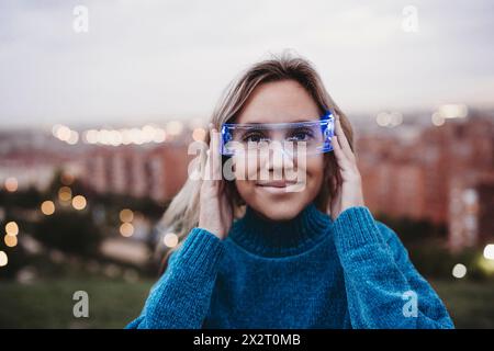 Lächelnde Frau, die in der Abenddämmerung eine kluge Brille trägt Stockfoto