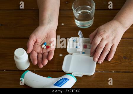 Hände einer Seniorin mit Kapseln und Pillen zu Hause auf dem Tisch Stockfoto