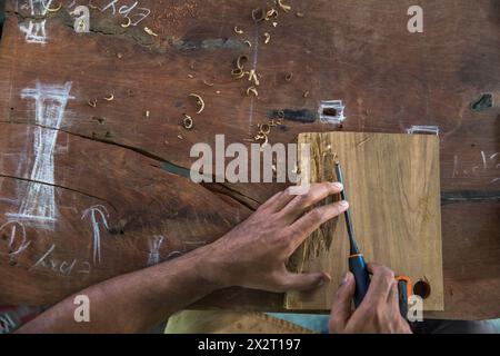 Hände des Zimmermanns, der Holzstücke auf Werkbank in der Werkstatt schnitzt Stockfoto