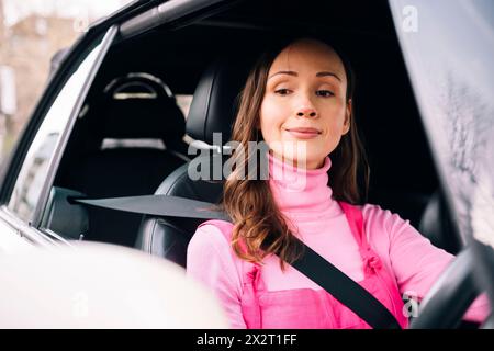 Frau, die im Auto sitzt und auf den Seitenspiegel blickt Stockfoto