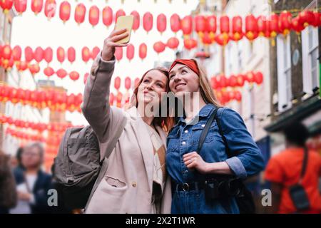 Lächelnde Freunde machen Selfie unter hängenden chinesischen Laternen in der Stadt Stockfoto