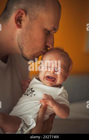 Vater küsst den schreienden Jungen zu Hause Stockfoto