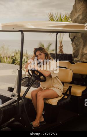 Junge Frau, die im Golfwagen sitzt Stockfoto