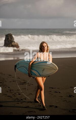 Junge Frau mit Surfbrett am Strand Stockfoto