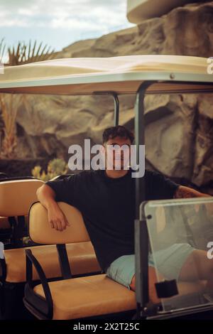 Junger Mann, der im Golfwagen sitzt Stockfoto