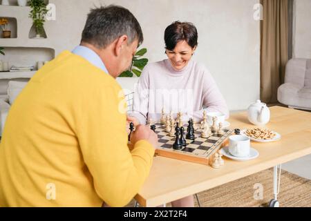 Reifes Paar, das zu Hause auf dem Tisch Schach spielt Stockfoto