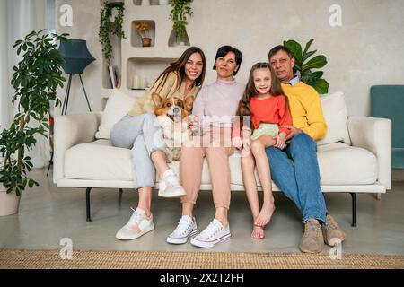 Glückliche Familie, die zu Hause mit Hund auf Sofa sitzt Stockfoto