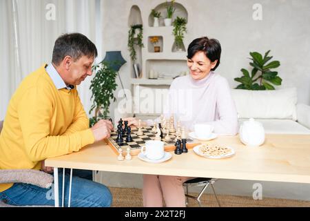 Paare spielen Schach am Tisch im Wohnzimmer Stockfoto