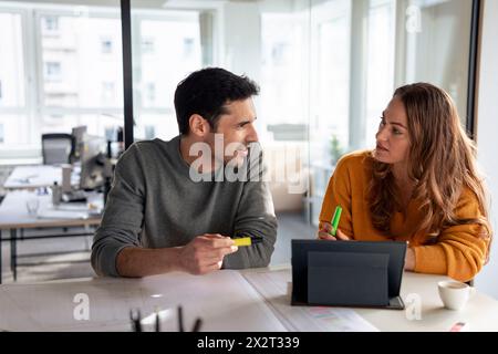 Architekten diskutieren mit Tablet-PC und Blueprints am Schreibtisch Stockfoto