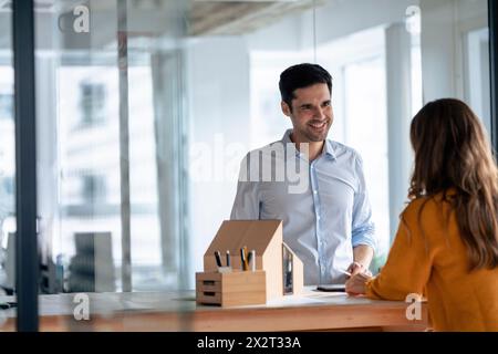 Lächelnde Architekten diskutieren mit Modellhaus am Schreibtisch Stockfoto