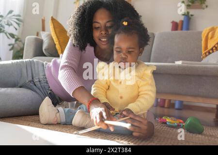 Junge Mutter und Tochter malen zusammen im Wohnzimmer Stockfoto