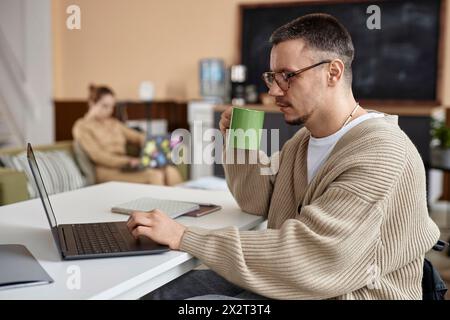 Geschäftsmann, der Tee trinkt und im Büro am Laptop arbeitet Stockfoto