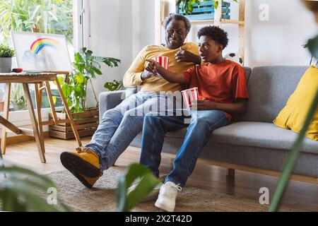 Großvater und Enkel mit Popcorn sehen zuhause das Spiel zusammen Stockfoto