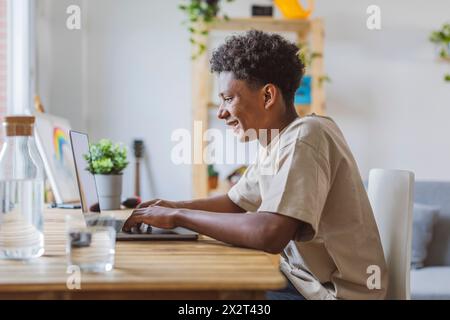 Lächelnder Teenager mit Laptop zu Hause Stockfoto