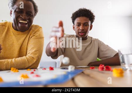 Glücklicher Seniorenmann, der mit Enkel zu Hause ein Brettspiel spielt Stockfoto