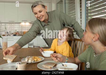 Lächelnde Frau serviert zu Hause Frühstück für Sohn und Tochter Stockfoto