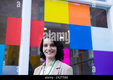 Lächelnde, schöne, reife Geschäftsfrau vor einem bunten Fenster Stockfoto