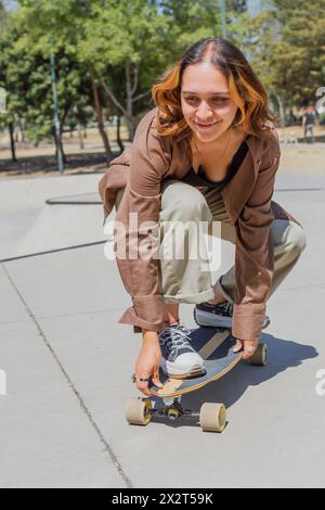 Lächelnde Frau, die an sonnigen Tagen im Park Skateboarden fährt Stockfoto