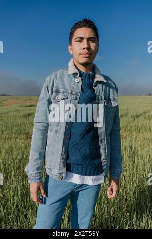 Mann mit Jeansjacke, der auf der Wiese steht Stockfoto