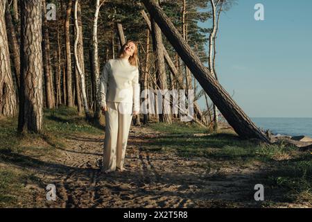 Eine Frau in weißer Kleidung geht einen Weg entlang, umgeben von der Natur. Stockfoto