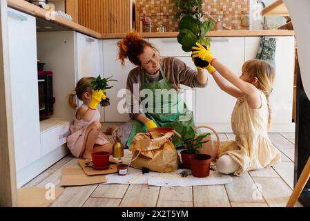 Mutter und Töchter halten Topfpflanzen in der Küche zu Hause Stockfoto