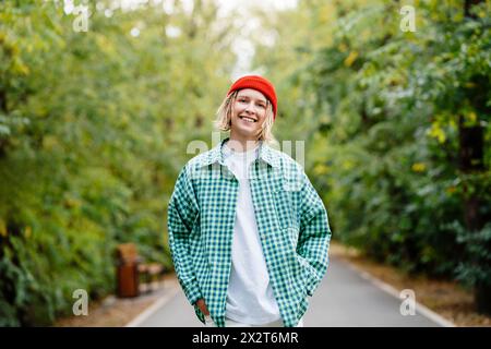 Glückliche junge Frau, die kariertes Hemd trägt und im Park steht Stockfoto