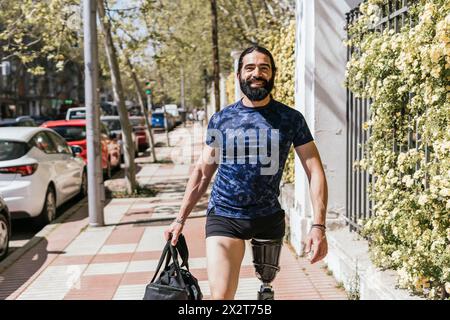 Lächelnder Athlet mit Beinprothetik auf dem Gehweg Stockfoto