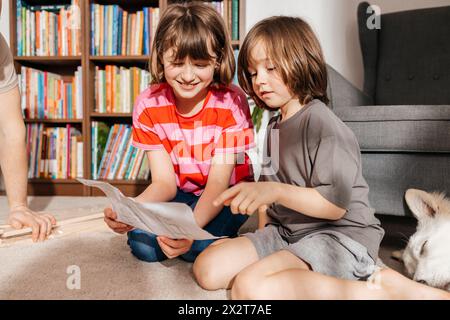 Geschwister lesen Anweisungen zum Zusammenbauen von Möbeln zu Hause Stockfoto