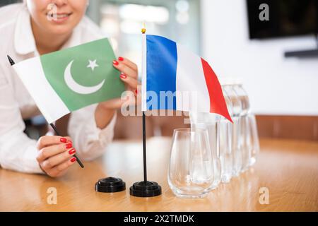 Vorbereitung auf Geschäftsverhandlungen - Frau setzt kleine Flaggen von Ländern Frankreichs und Pakistans auf den Tisch Stockfoto