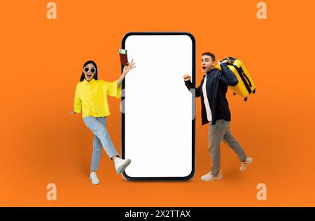 Glückliche junge Reisende neben leerem Smartphone-Mockup Stockfoto