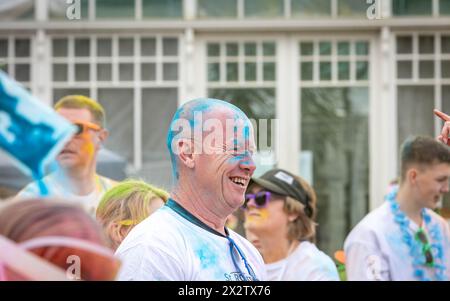 Der Mann lacht, nachdem er sich beim Colour Run mit farbigem Pulver über den Kopf gegossen hat Stockfoto