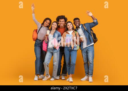 Glückliche Schüler, die auf orangem Hintergrund Abschied winken oder grüßen Stockfoto