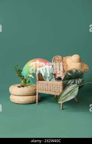 Rattan-Sessel mit Strandaccessoires, Glas Cocktail und Palmblättern auf farbigem Hintergrund Stockfoto