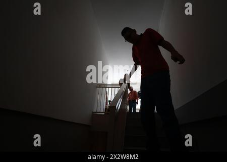 Maracay, Venezuela. April 2024. Der Venezolaner Jeison Rodriguez (r) geht die Treppe hinunter in seinem Haus. Rodriguez erhielt Schuhe, die der deutsche Schuhmacher Wessels speziell für seine langen Füße schuf. Quelle: Jesus Vargas/dpa/Alamy Live News Stockfoto