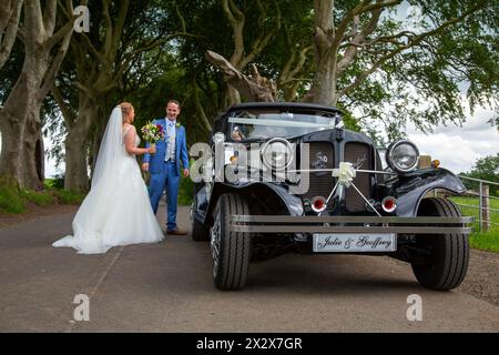 16.07.2019, Stranocum, Nordirland, Vereinigtes Königreich - Hochzeitspaare, die in einem Vintage Bentley reisen, besuchen Sie die Dark Hedges, eine majestätische Buchenallee Stockfoto