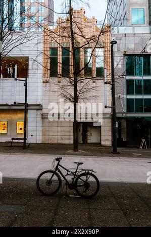 Ein Fahrrad, das an einem Stand auf dem Bürgersteig der Granville Street mit farbigen Gebäuden und blattlosen Bäumen befestigt ist Stockfoto