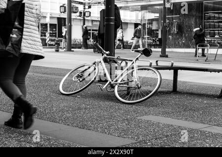 Vancouver, Kanada - 23. Februar 2024: Ein Schwarzweißfoto eines Fahrrads, das auf einer Bank auf dem Bürgersteig der Granville Street steht Stockfoto