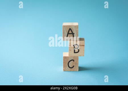 Drei Spielzeugblöcke aus Holz mit den Buchstaben ABC darauf. Auf blauem Hintergrund, Kopierraum. Stockfoto