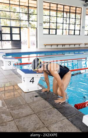 Birassische junge Schwimmerin, die eine Schutzbrille trägt und sich auf das Tauchen vorbereitet, Kopierraum Stockfoto