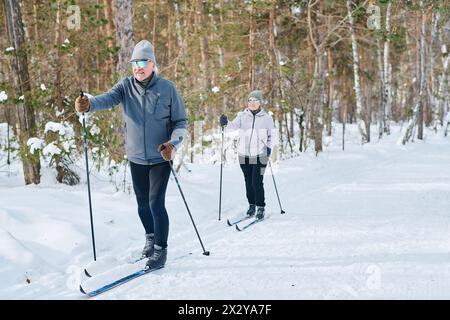 Große Aufnahme von älteren Männern und Frauen in Sportbekleidung, Skifahren zusammen im Waldpark am Wintertag, Kopierraum Stockfoto