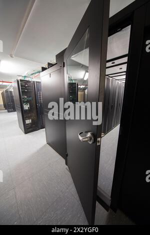 Offene Tür in abgedichtetem Korridor mit Telekommunikationsregalen. Stockfoto