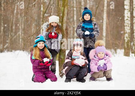 Porträt von fünf Kindern, die im Winterpark Schneebälle in der Hand halten Stockfoto