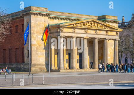 Die neue Wache (englisch: New Watchhouse), ein historisches Gebäude in Berlin, steht unter klarem Himmel, mit Besuchern am Eingang. Stockfoto