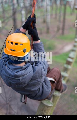 Ein kleiner Kletterer läuft auf Baumstämmen, die ein Sicherheitsseil halten Stockfoto