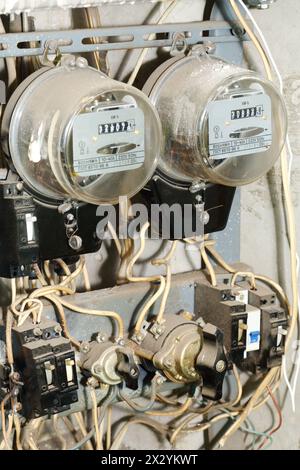 Zwei alte, schmutzige Stromzähler mit vielen Drähten, Schaltern und Ventilen. Stockfoto