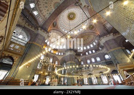 Menschen in der großen, schönen und alten Neuen Moschee (Yeni Cami) in Istanbul, Türkei. Die zentrale Kuppel hat eine Höhe von 36 m und einen Durchmesser von 17,5 m. Stockfoto